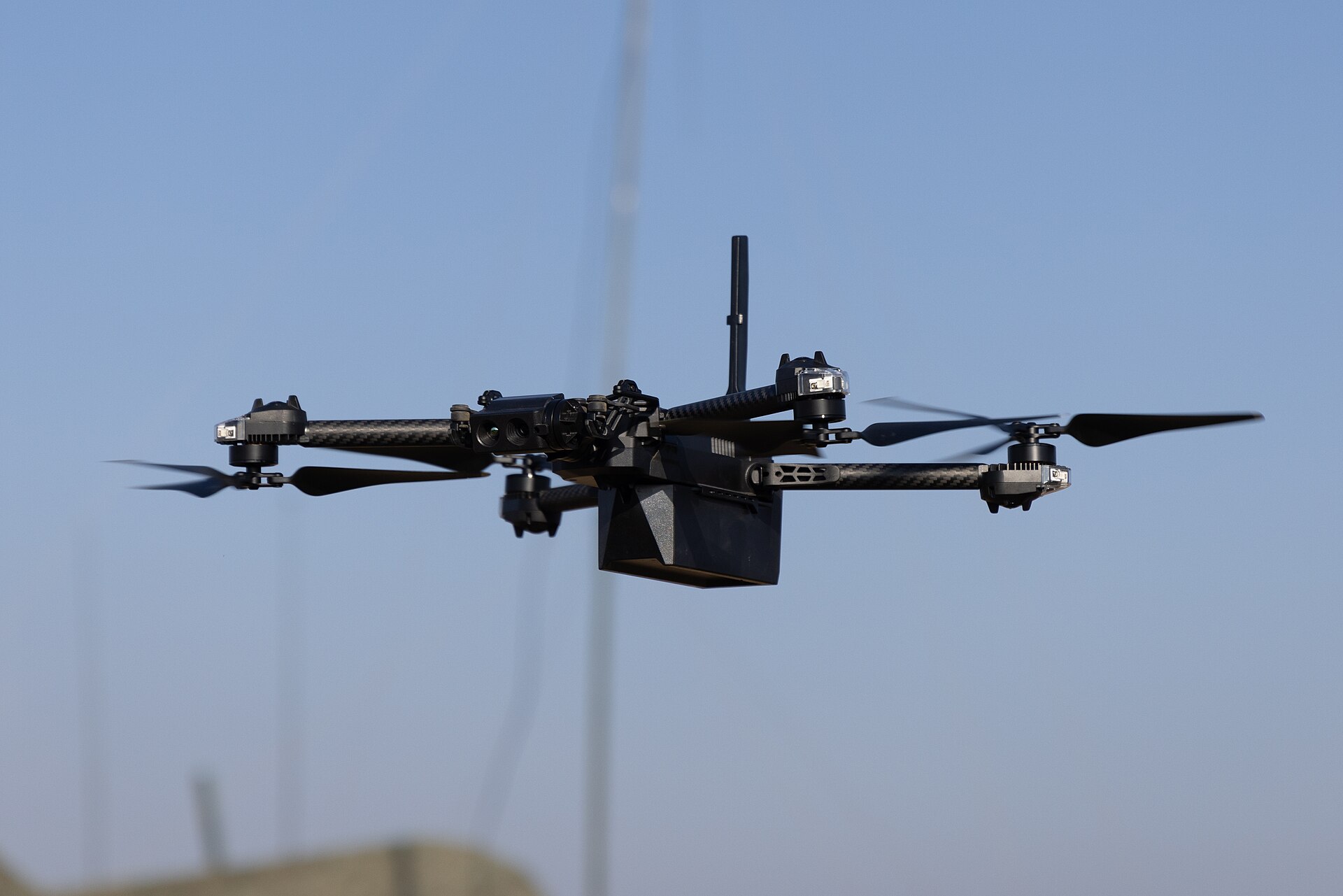 A close-up view of a Skydio drone flying against a blue sky.