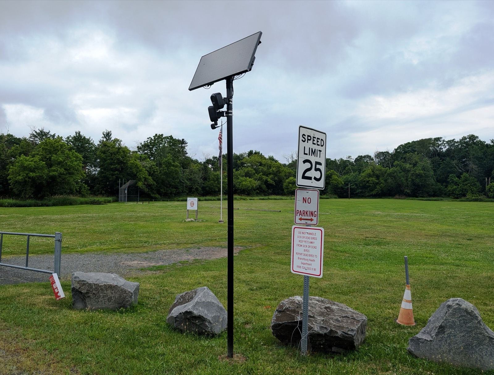 Two Flock Safety automated license plate reader cameras mounted beneath a solar panel beside a road.