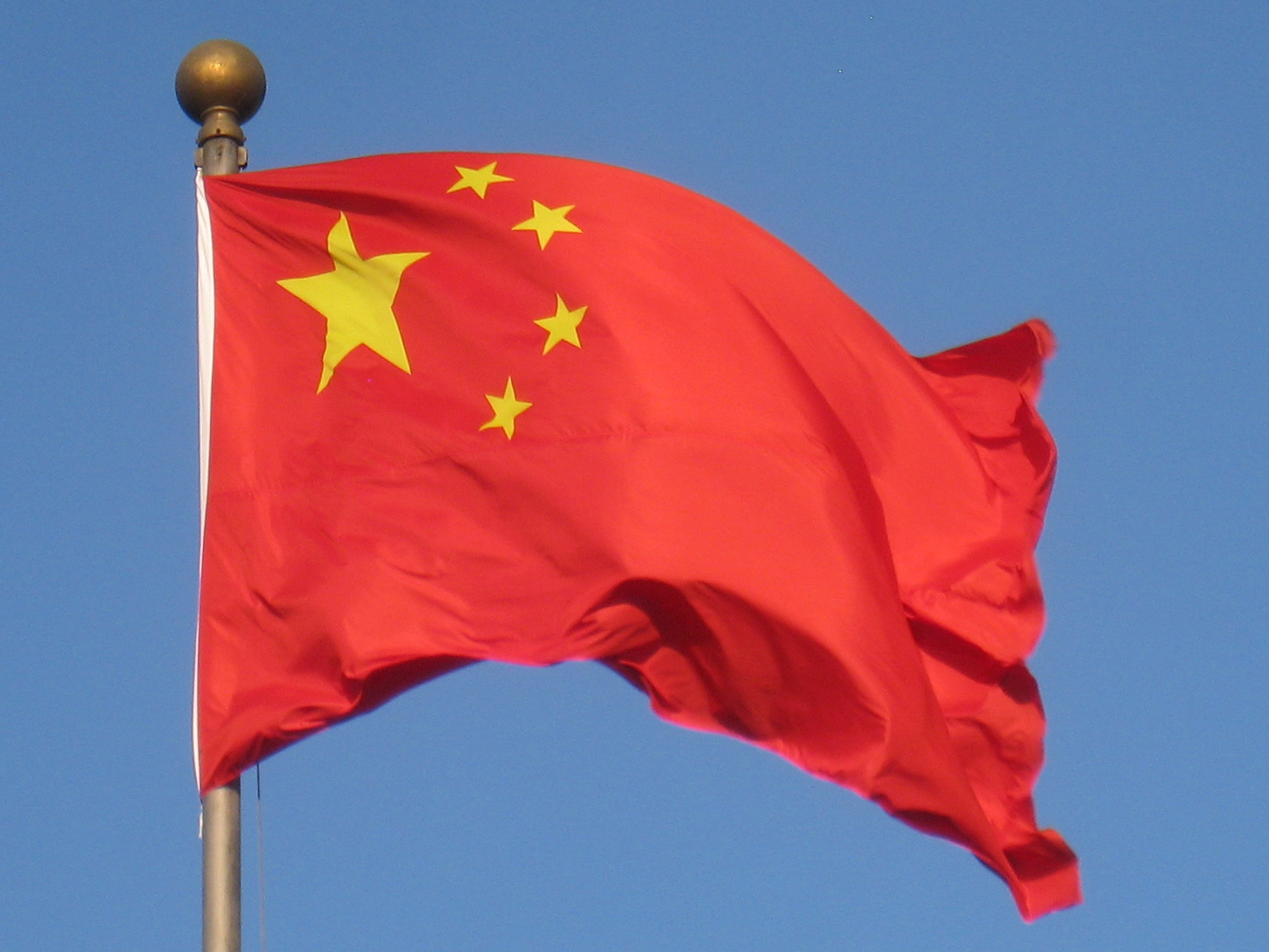 China’s red flag with yellow stars waving against a blue sky in Beijing.