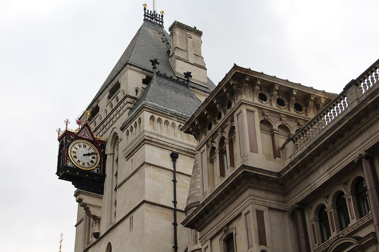 A close view of the clock tower and stone facade of the Royal Courts of Justice in London