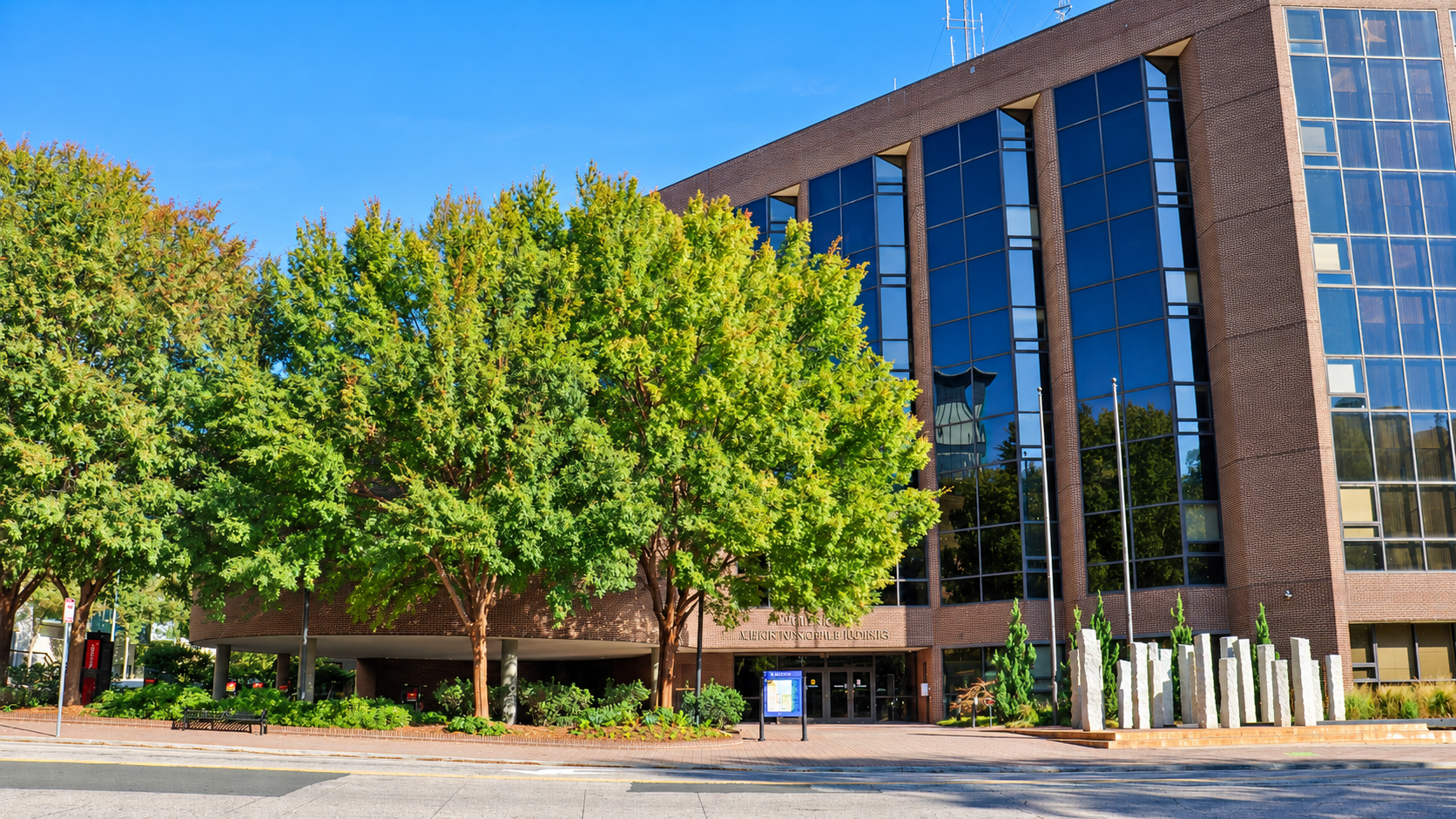An AI-enhanced view of Raleigh Municipal Building, with trees and a stone sculpture outside.